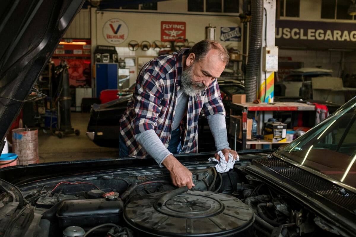Mechanic hunting for rust under bonnet of a car